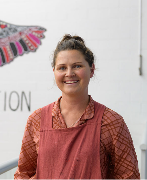Lara Went, Worimi artist, standing in front of her artwork