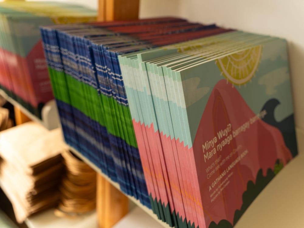 Stacks of the Gathang language picture book ‘Minya Wuy? Mara nyaaga barragay barrayga’ on a shelf